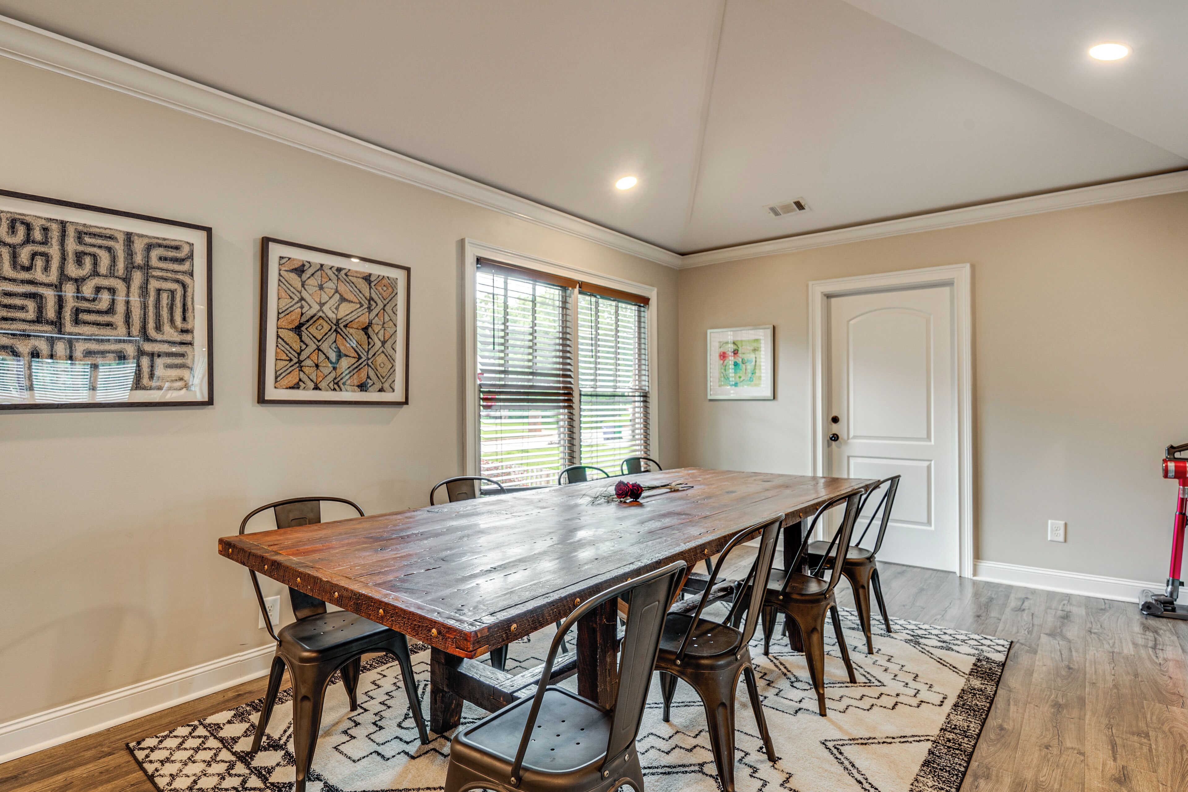 A dining area with a wooden table, six chairs, and artwork on the walls.