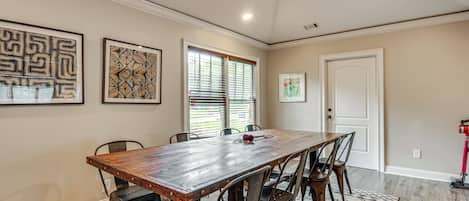A dining area with a wooden table, six chairs, and artwork on the walls.