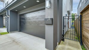 A residential garage with a metal gate, a concrete driveway, and a grey exterior wall. - Game Room & Private Yard! Family Escape in Houston (Houston)