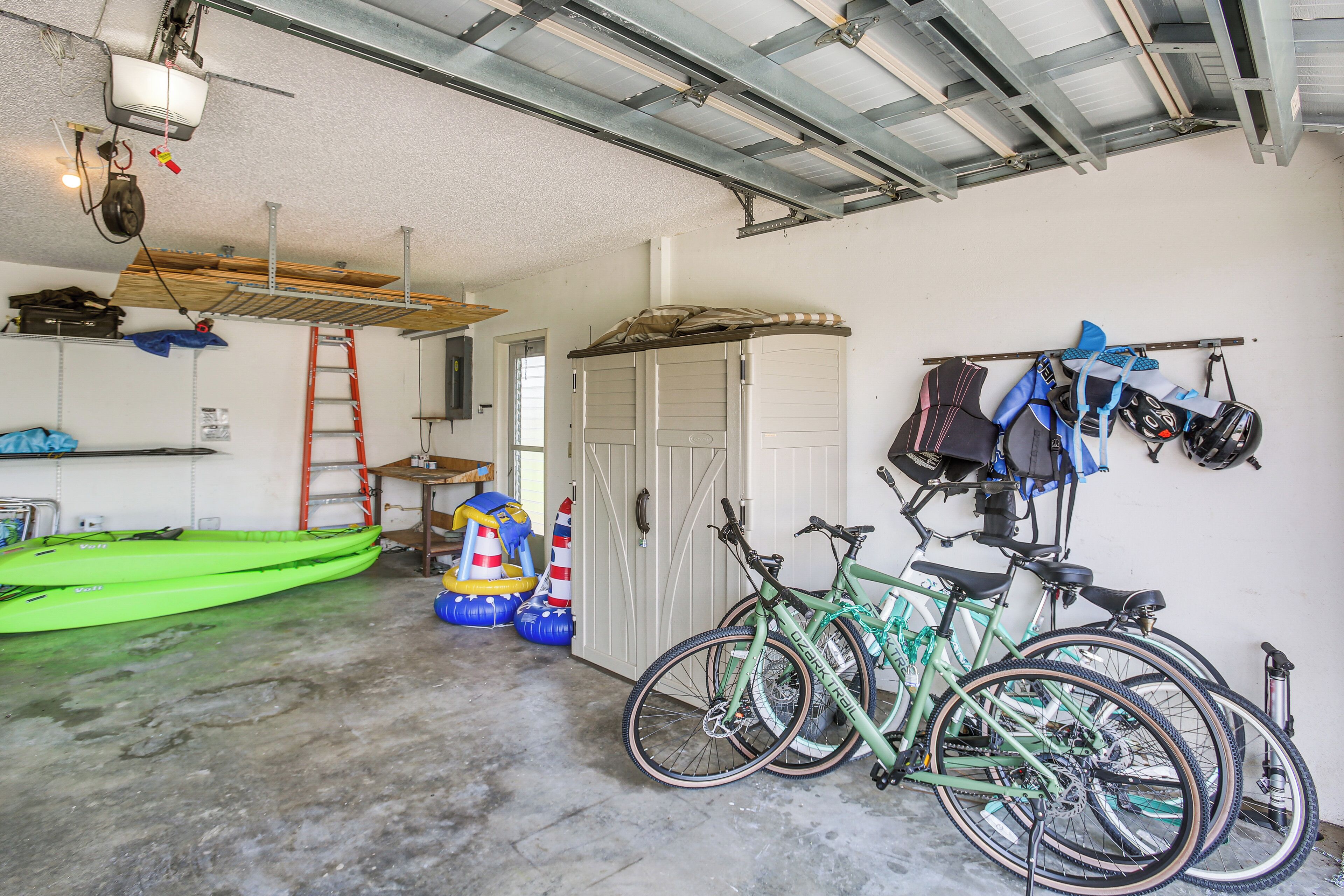 A garage with bicycles, a kayak, and a ladder.