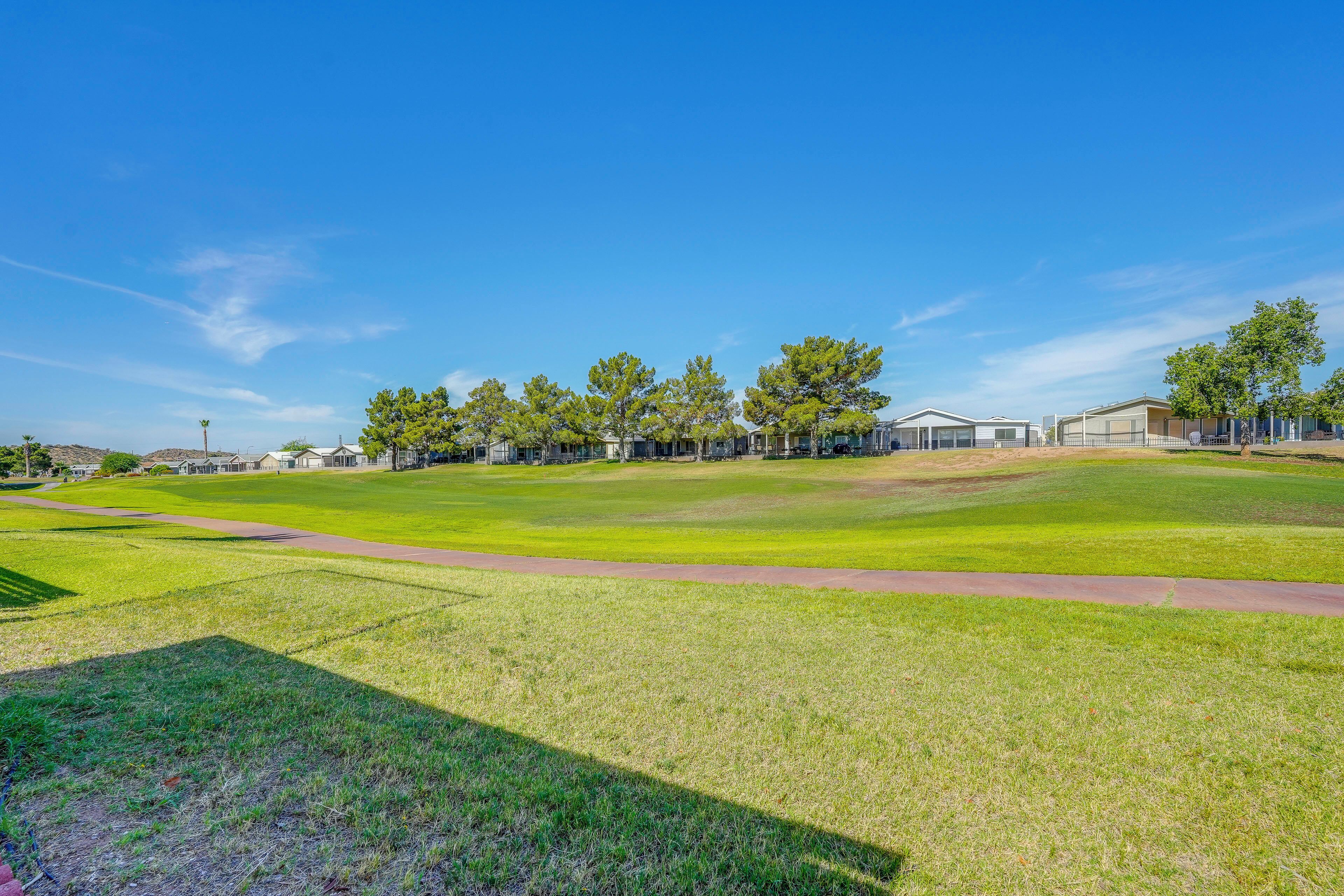 A golf course with a clear sky, green grass, and a walking path.