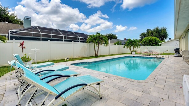 Ein Garten mit Swimmingpool, Liegestühlen und einer überdachten Terrasse.