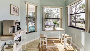 A kitchen with a coffee maker, a table, and chairs, a window with a view of trees, and a ceiling fan. - Resort Condo Near Anna Maria Island & IMG Academy (Bradenton)