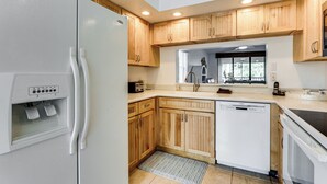 A modern kitchen with wooden cabinets, a white refrigerator, a Bosch dishwasher, and a built-in window. - Resort Condo Near Anna Maria Island & IMG Academy (Bradenton)
