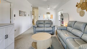A living room with a grey leather sofa, a round wooden coffee table, and a ceiling fan. - Resort Condo Near Anna Maria Island & IMG Academy (Bradenton)