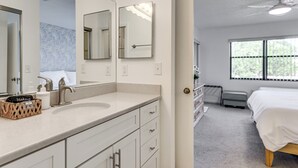A hotel room with a large mirror, a sink, a bed, and a window with a view of trees. - Resort Condo Near Anna Maria Island & IMG Academy (Bradenton)
