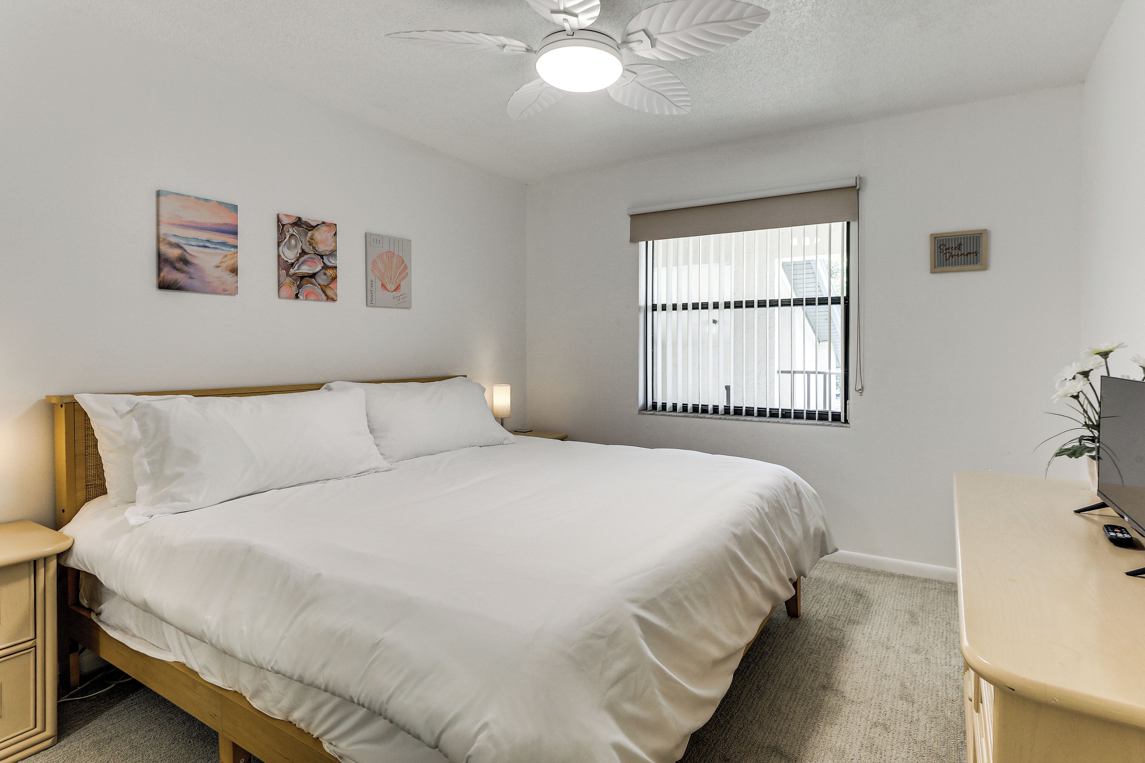 A bedroom with a bed, bedside tables, a desk, and a window with blinds.