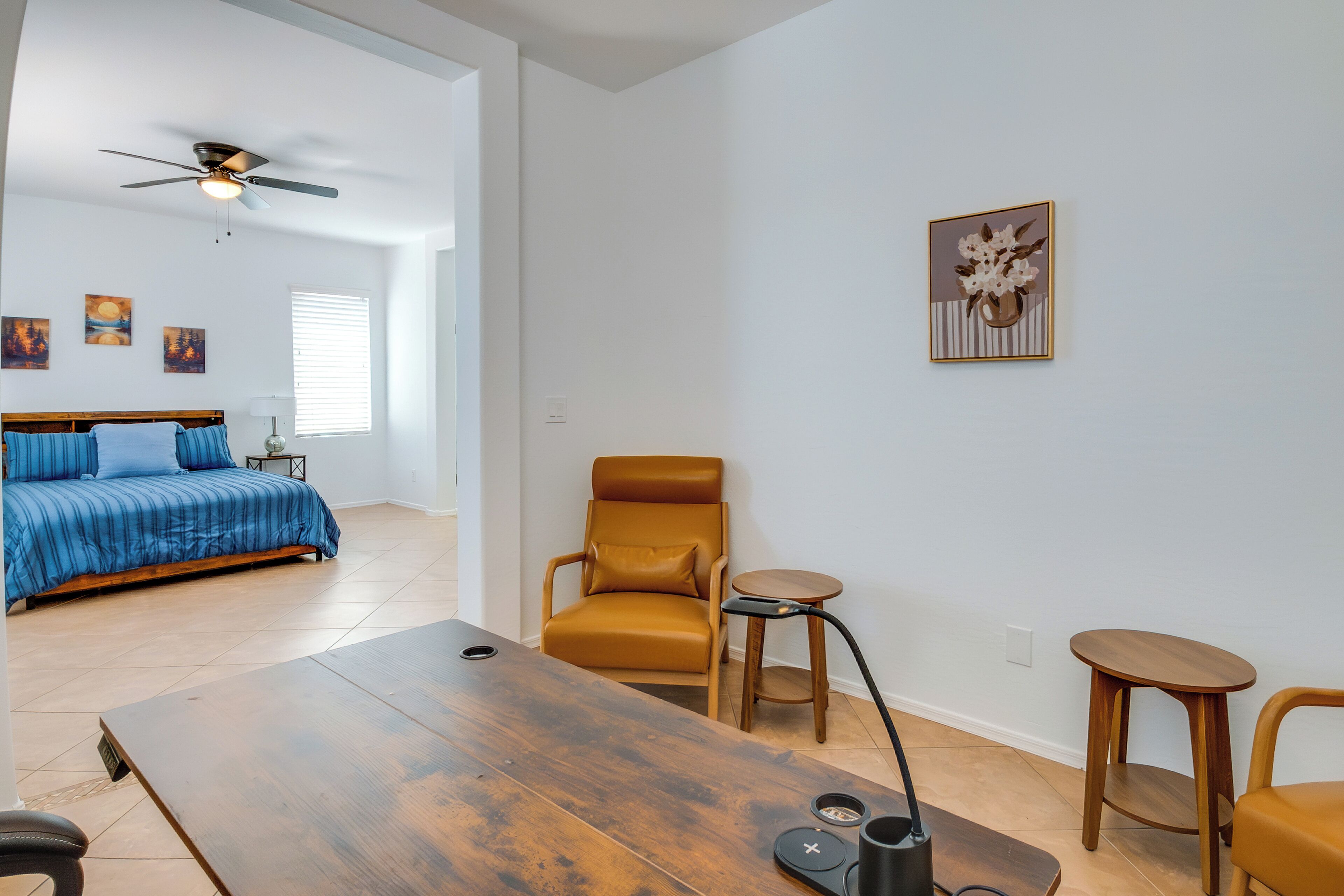 A modern room with a bed, a chair, a table, and a ceiling fan.