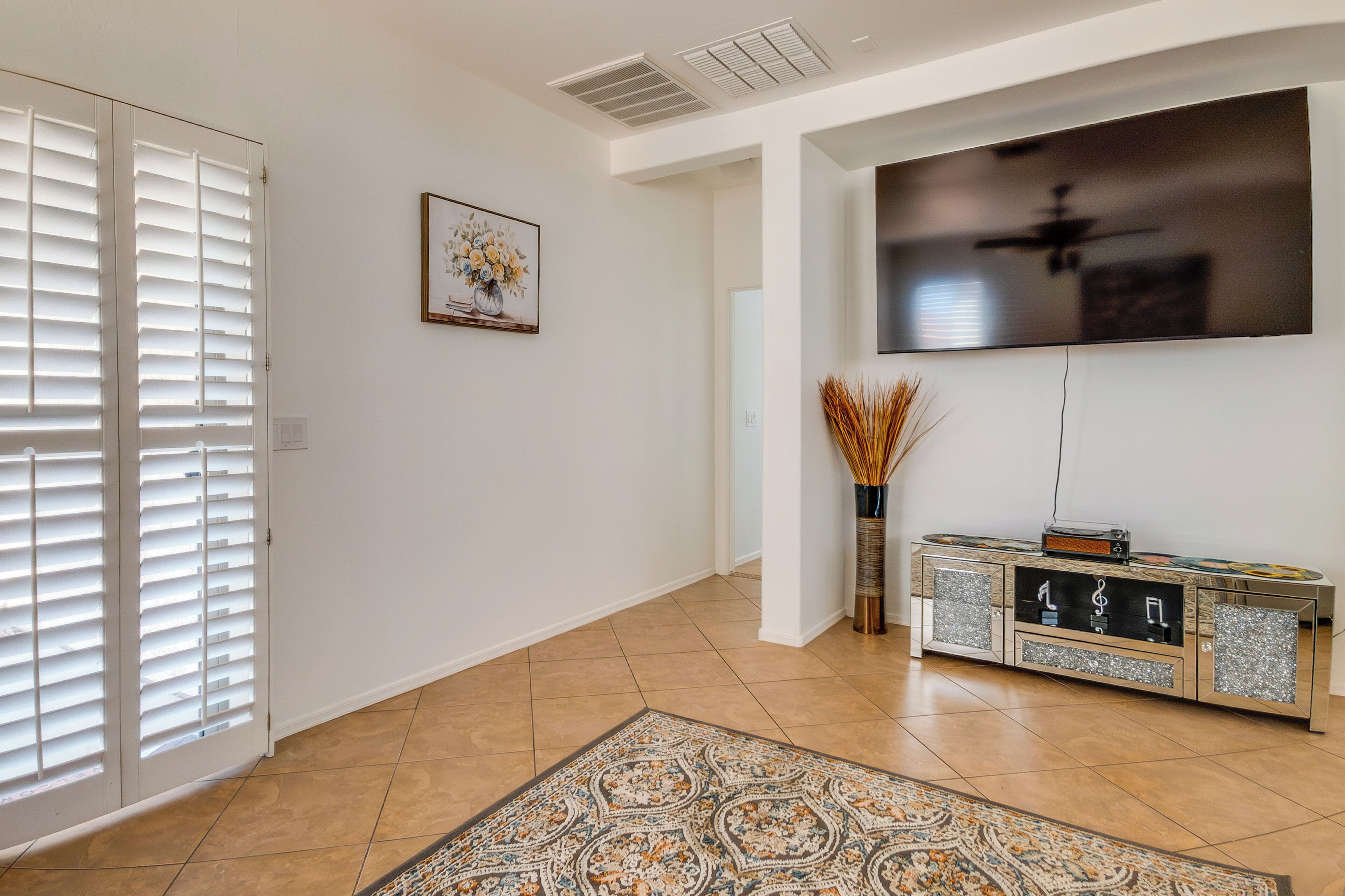 A modern living room with a flat-screen TV, a decorative cabinet, and a patterned rug.