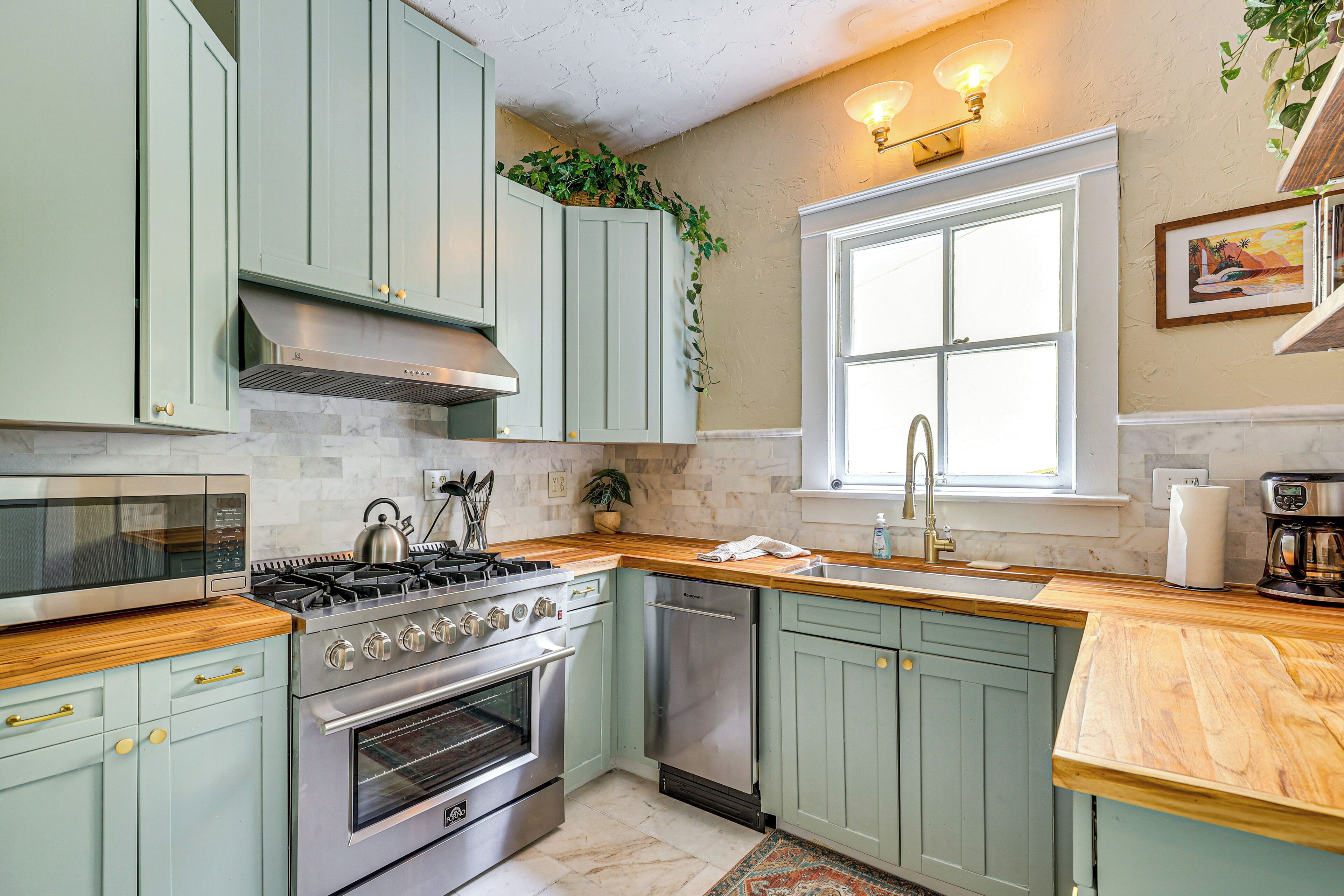 A kitchen with light green cabinets, a stove, oven, and a sink.