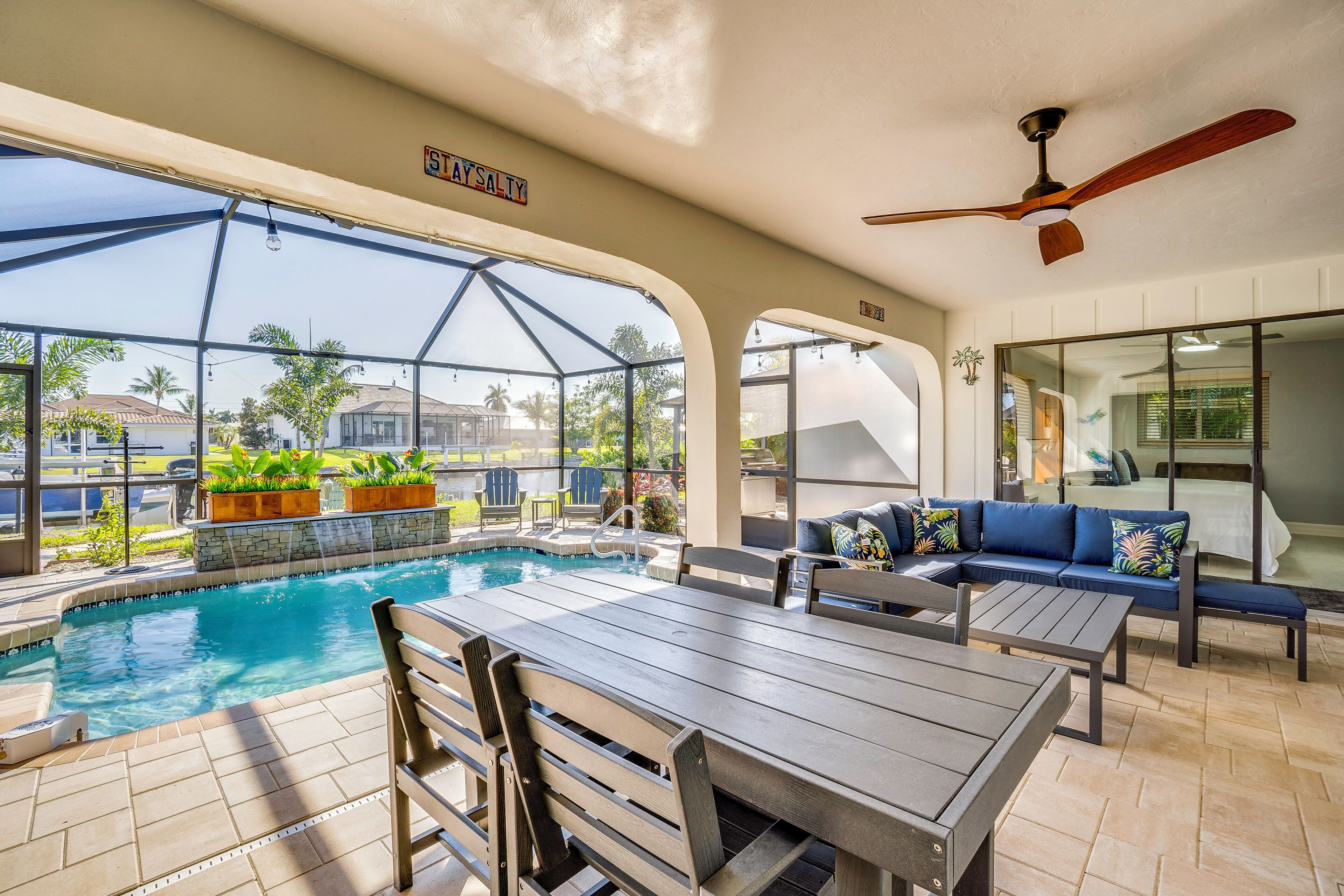 A pool area with a glass enclosure, outdoor seating, and a ceiling fan.