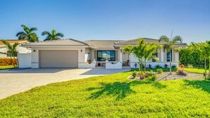 A modern house with a garage, a covered patio, and a well-maintained lawn. - Waterfront Pgi, Heated Pool, Dock, 2 King Suites (Punta Gorda)