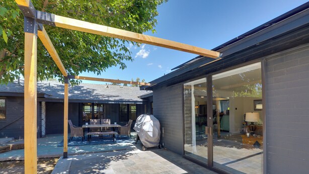 Eine moderne Terrasse mit überdachtem Grill, Essbereich und einer Garage mit großen Schiebetüren.