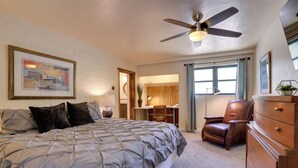 Ein Schlafzimmer mit einem Bett, einem Deckenventilator, einer Kommode und einem Schreibtisch.