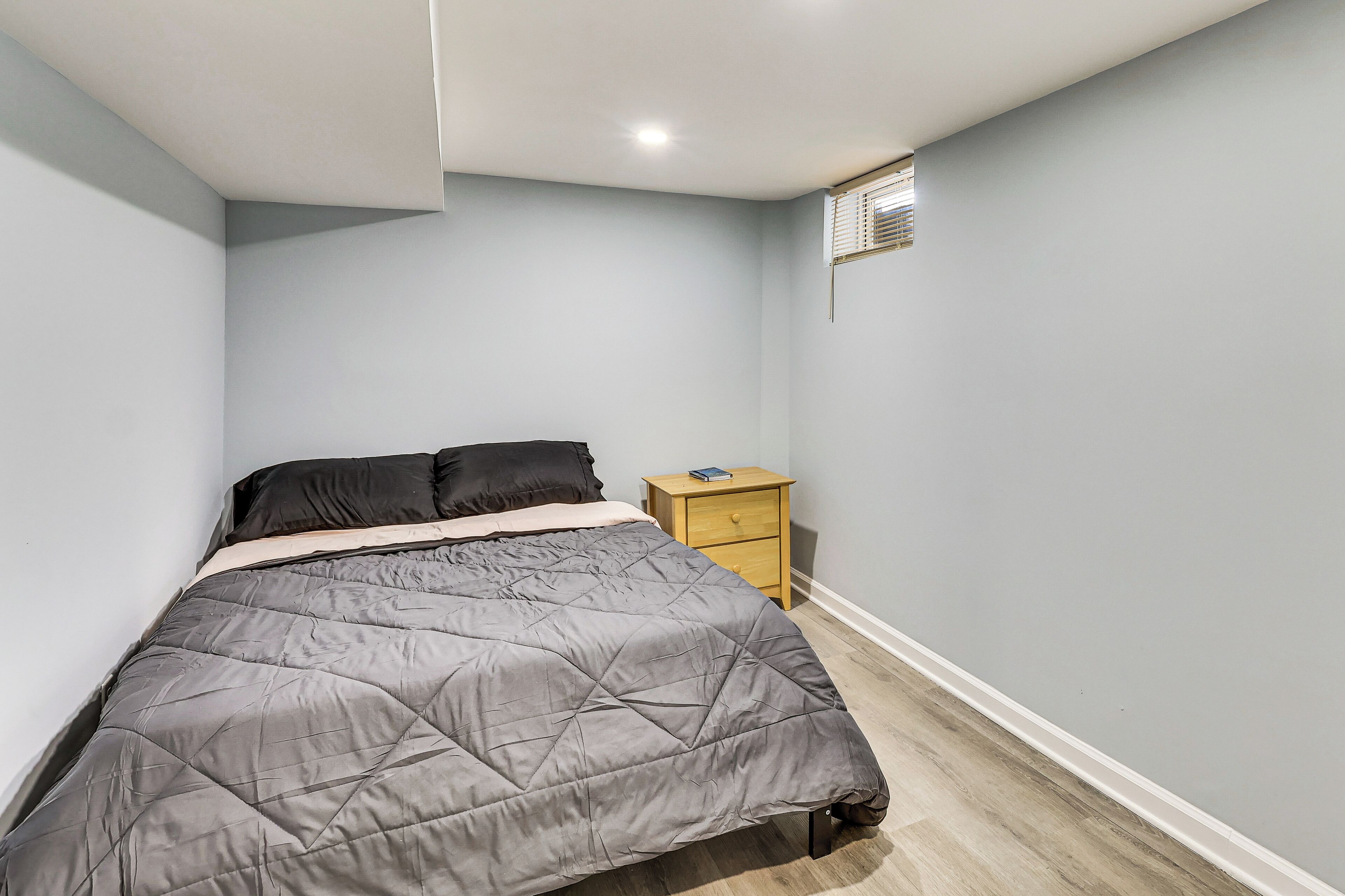 A bedroom with a bed, a nightstand, and a window.