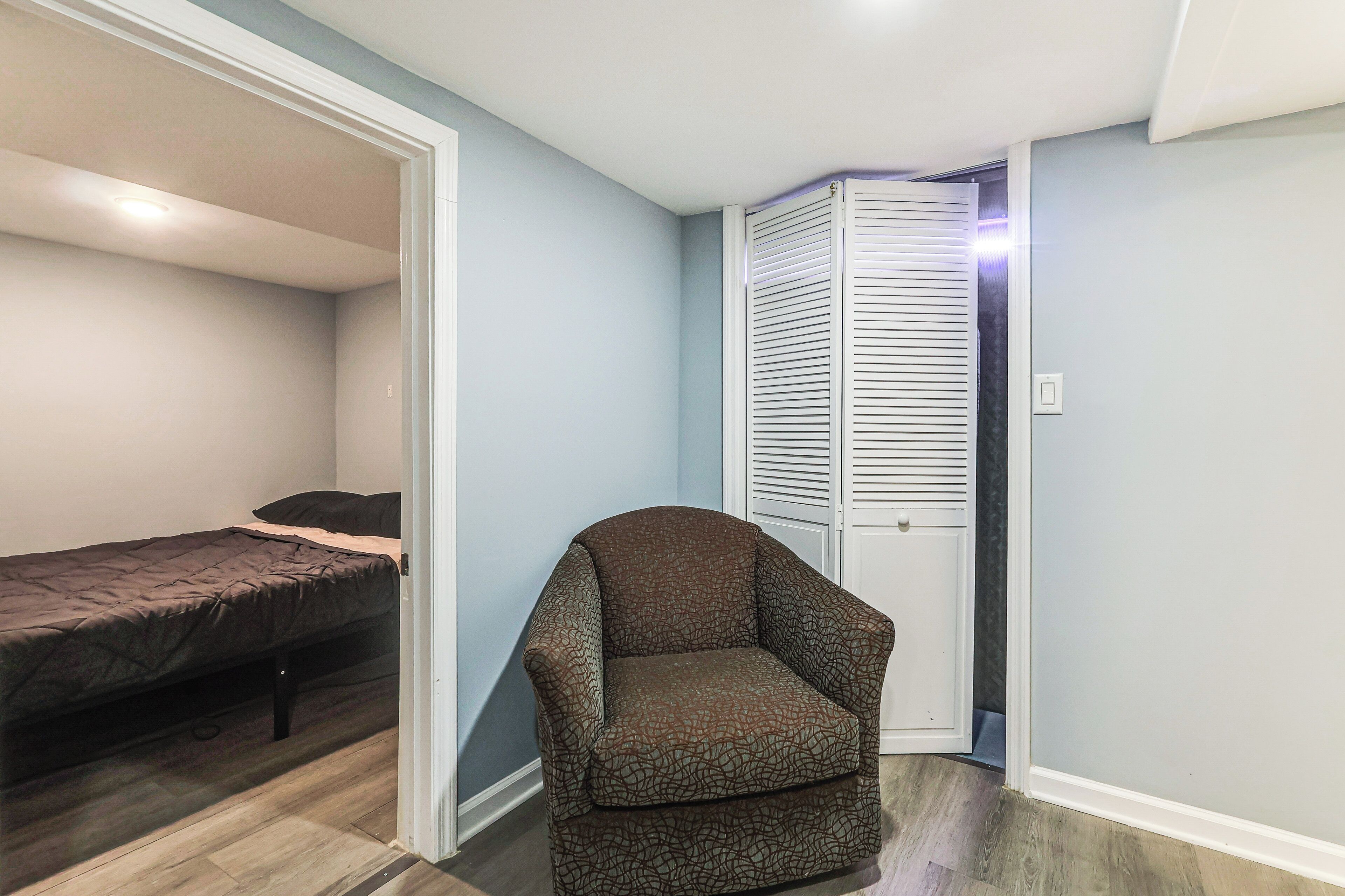 Une chambre à coucher comprenant un lit, une chaise et une armoire à portes à persiennes.