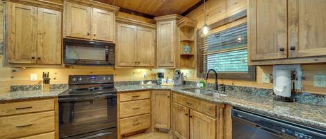 A kitchen with wooden cabinets, a stove, microwave, and dishwasher.