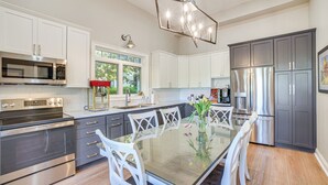 A modern kitchen with stainless steel appliances, white cabinetry, and a glass dining table. - 4 Mi to Saratoga Course! Resort-style Condo (Saratoga Springs)