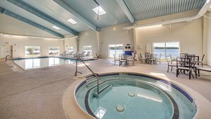 An indoor swimming pool with a tiled edge, lounge chairs, and tables arranged around the pool area. - 4 Mi to Saratoga Course! Resort-style Condo (Saratoga Springs)