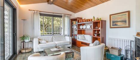 A modern living room with a white sofa, a coffee table, and a bookshelf.