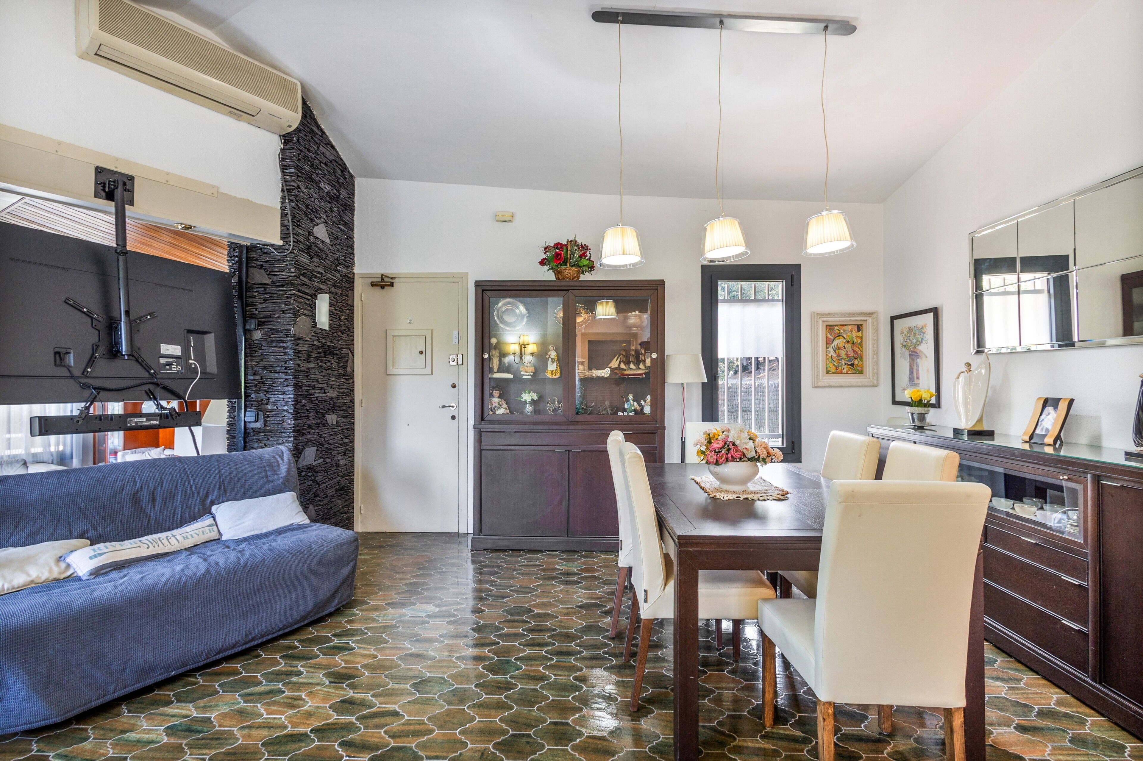 Una sala moderna con sofá, mesa de comedor, sillas y una cocina con refrigerador, estufa y alacenas.