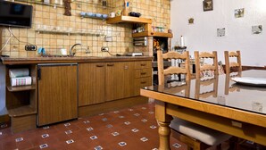 A kitchen with a tiled backsplash, wooden cabinets, a dining table with chairs, and a tiled floor.