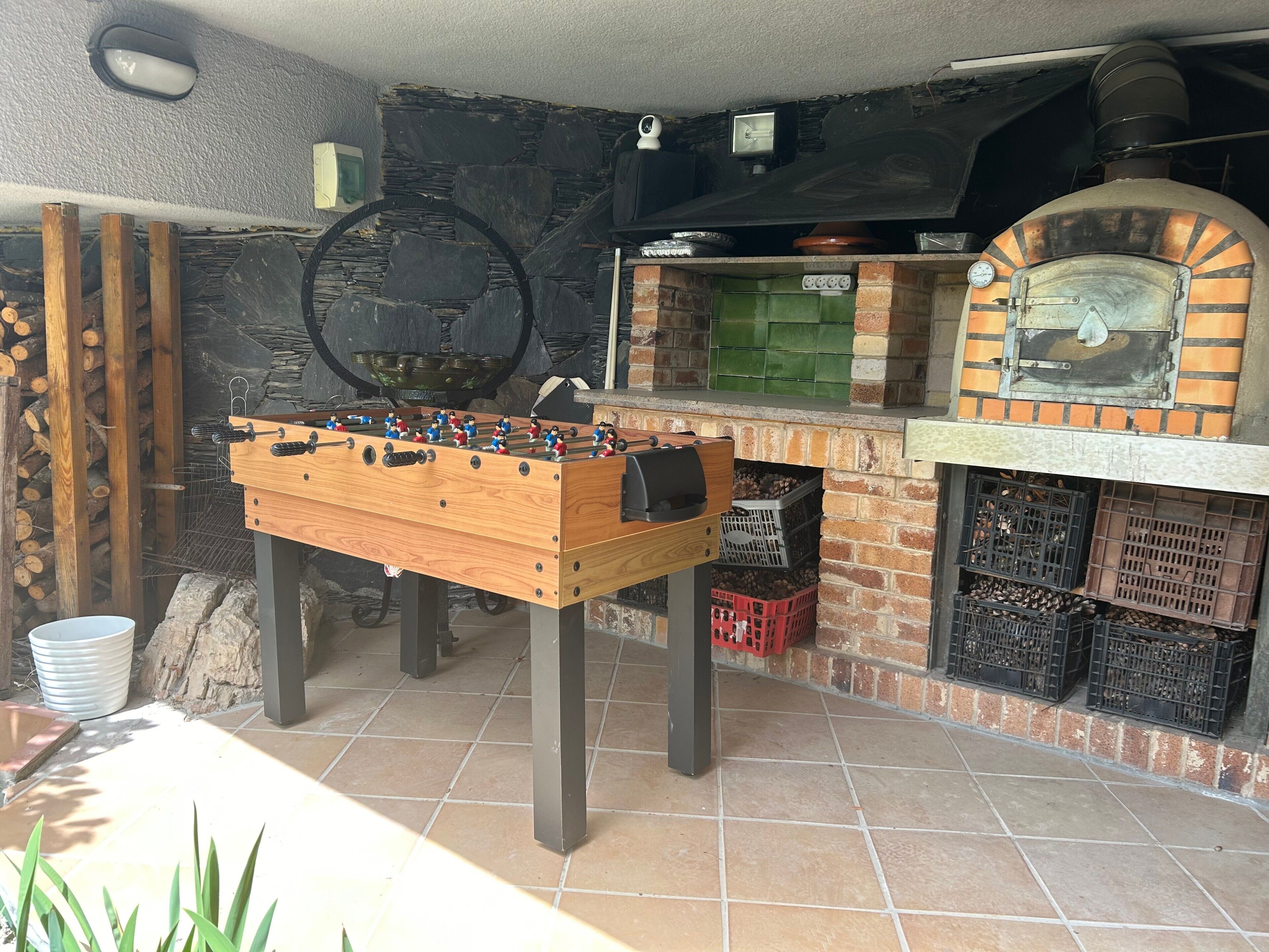Een tafelvoetbaltafel, een bakoven en een stenen muur.