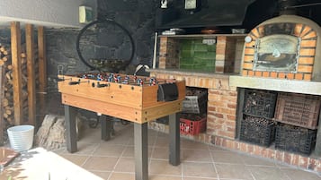 Een tafelvoetbaltafel, een bakoven en een stenen muur.