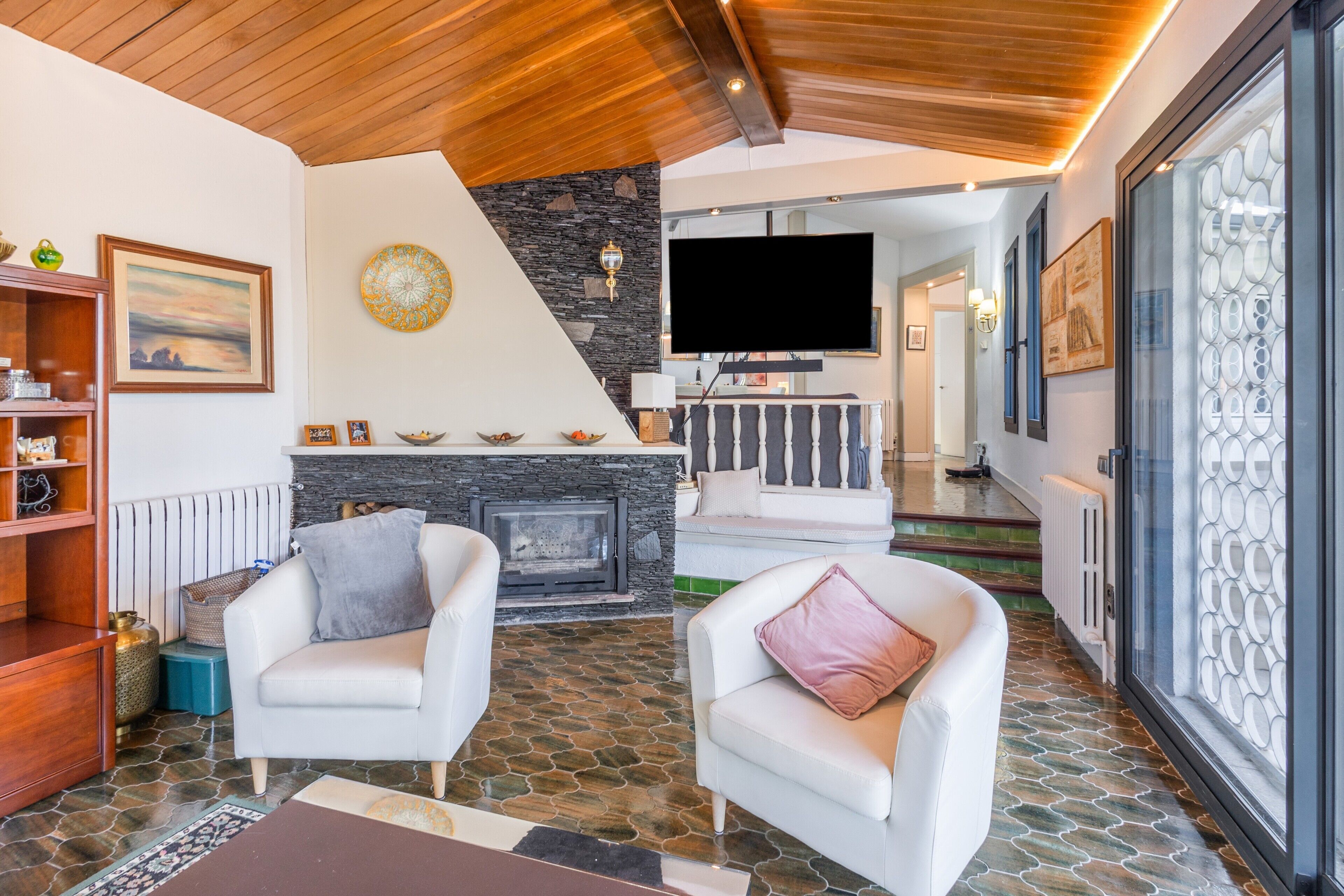Una sala de estar moderna con chimenea, sofás blancos y un televisor.