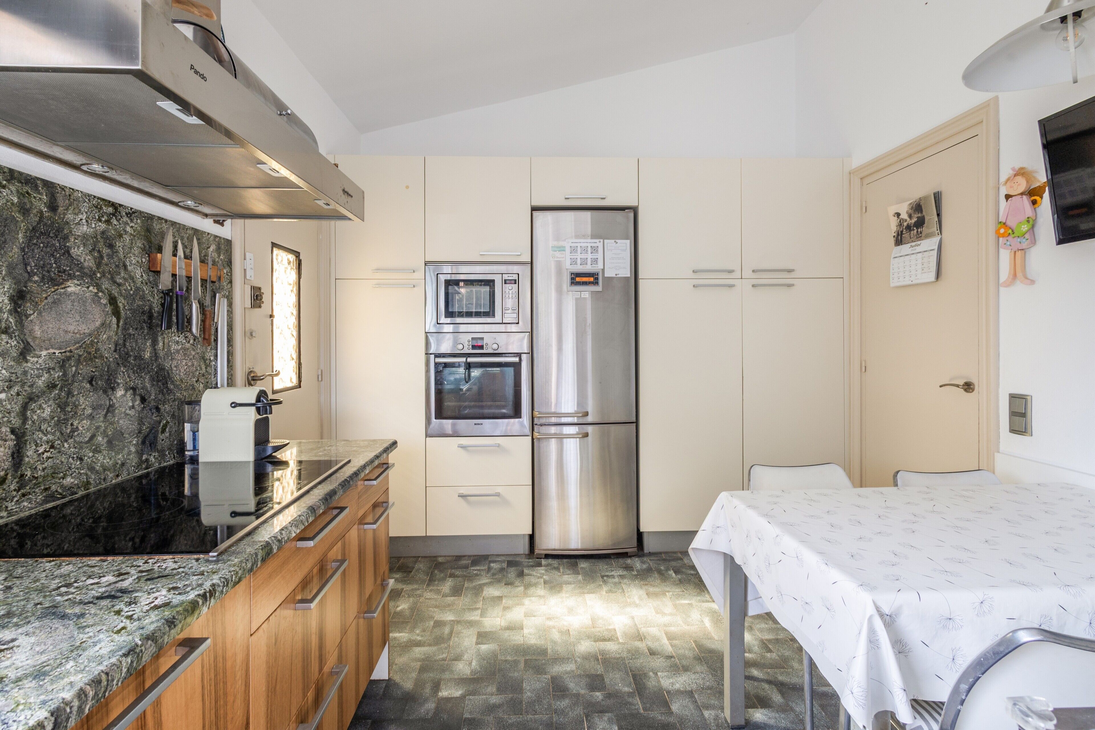 A compact kitchen with a built-in oven, a refrigerator, and a dining area with a table.