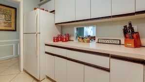 A kitchen with white cabinets, a white refrigerator, and a 'BIENVENUE' sign on the counter. - Island Walk to Ocean, Dining w/ Boat Dock & Lift! (Jensen Beach)