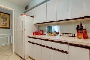 Une cuisine avec des meubles blancs, un réfrigérateur blanc et une pancarte « BIENVENUE » posée sur le comptoir.