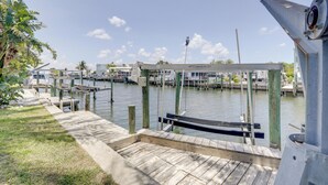 A marina with docked boats, a wooden pier, and a covered seating area. - Island Walk to Ocean, Dining w/ Boat Dock & Lift! (Jensen Beach)