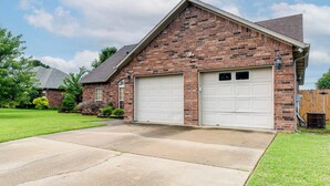 A two-story brick house with a garage, a front lawn, and a wooden fence.