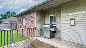 A house with a brick exterior, a wooden deck, and a barbecue grill.