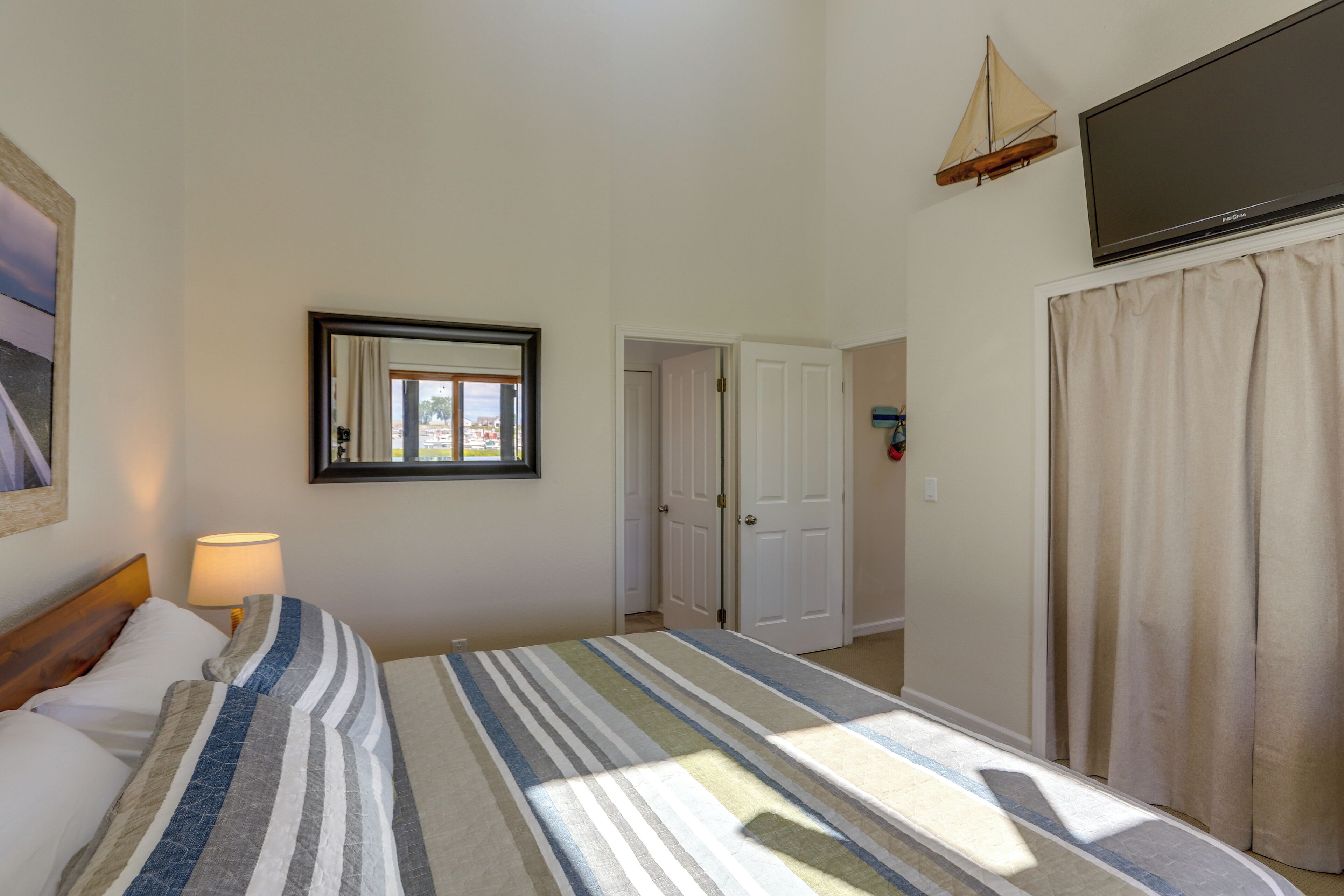 Une chambre à coucher avec un lit, une lampe de chevet, une fenêtre, une porte et un téléviseur.