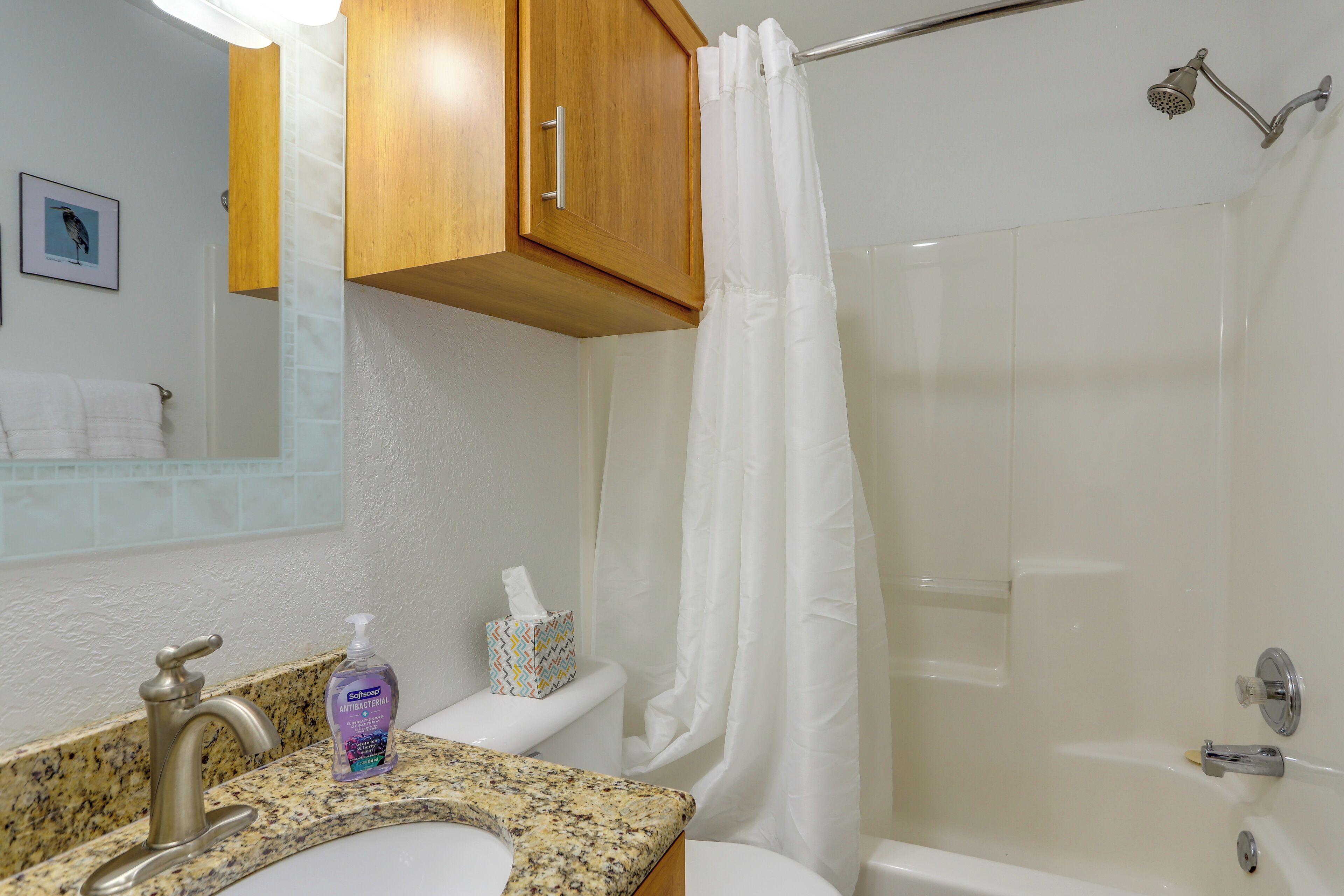 A bathroom with a sink, toilet, shower, and wooden cabinets.