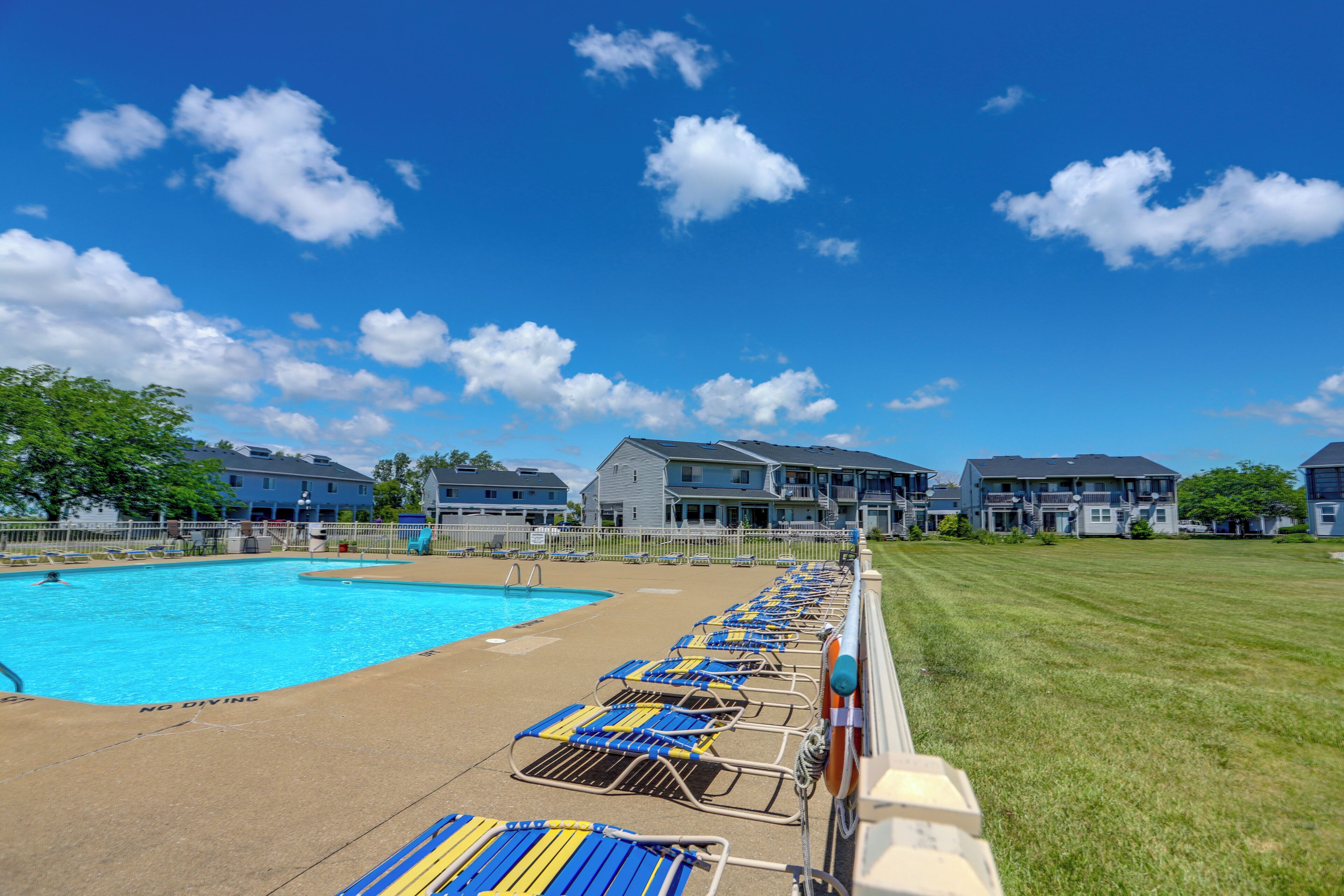 A swimming pool with lounge chairs, a 'NO DIVING' sign, and residential buildings in the background.
