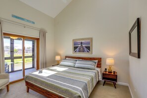 A bedroom with a bed, two bedside tables with lamps, a framed picture on the wall, and a view of the outdoors through a sliding glass door. - Lake View, Dock & Pool: Green Cove Resort Condo (Oak Harbor)