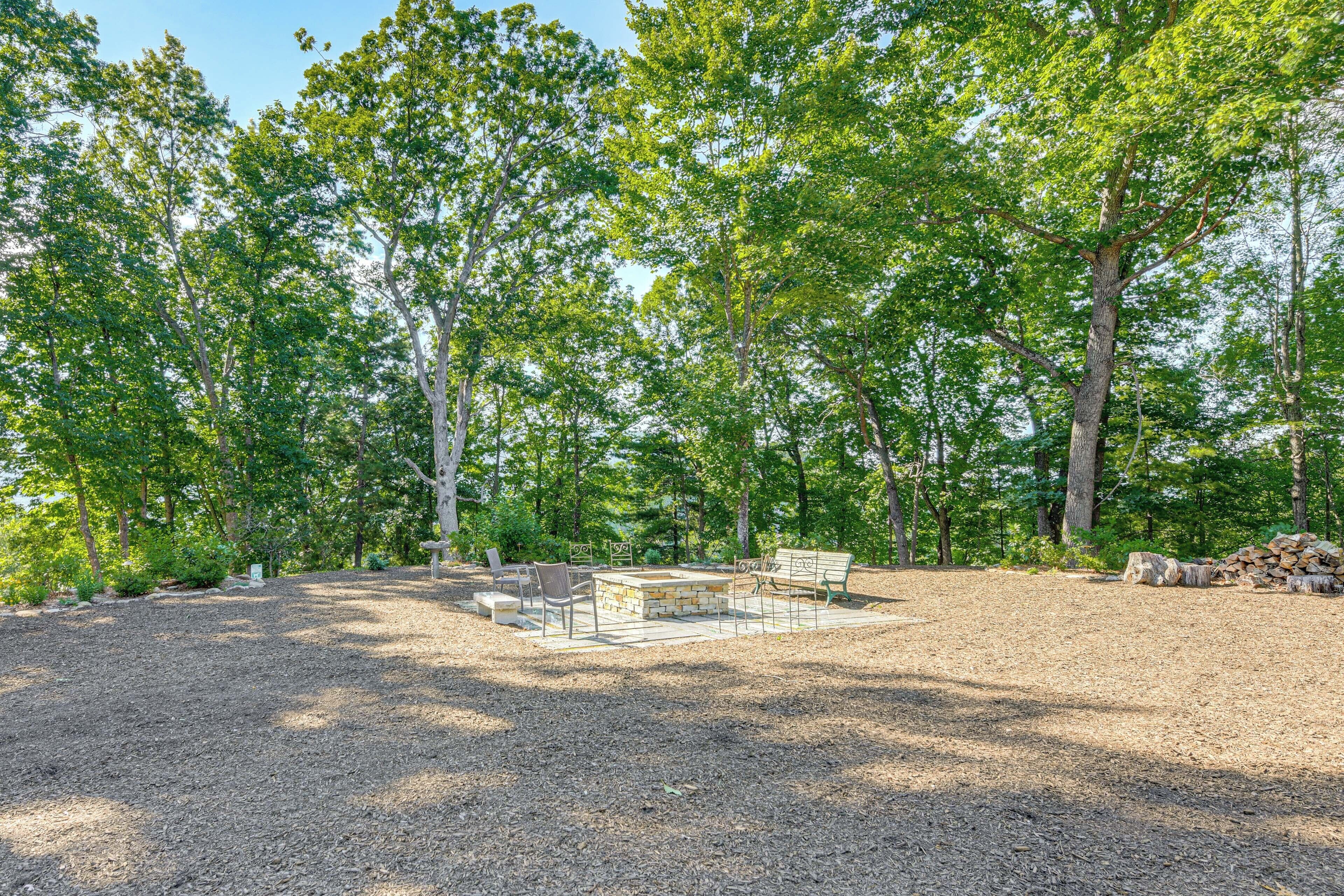 Un parc équipé d’un foyer, de bancs et d’une pile de bûches.