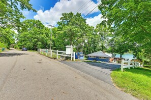 A residential street with houses, a clear sky, and a lake in the background.