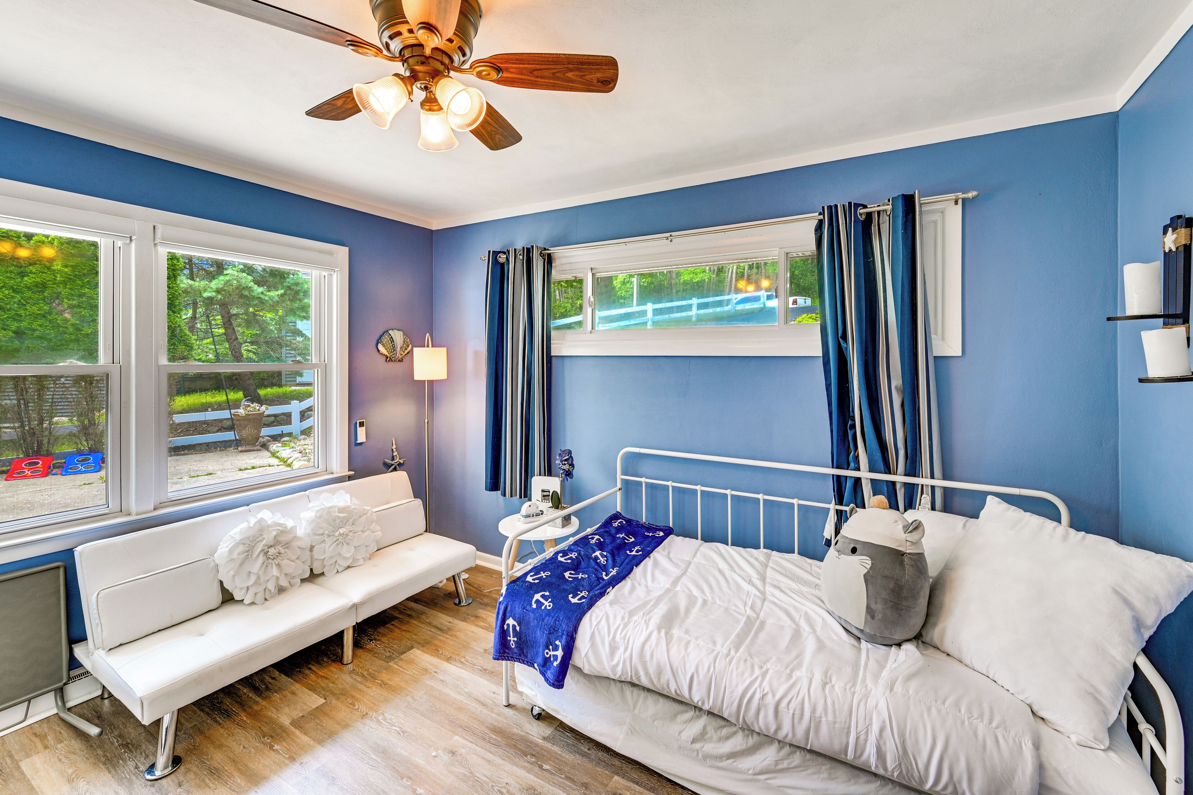 A bedroom with a bed, a bench, a window, and a ceiling fan.