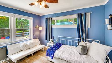 A bedroom with a bed, a bench, a window, and a ceiling fan.