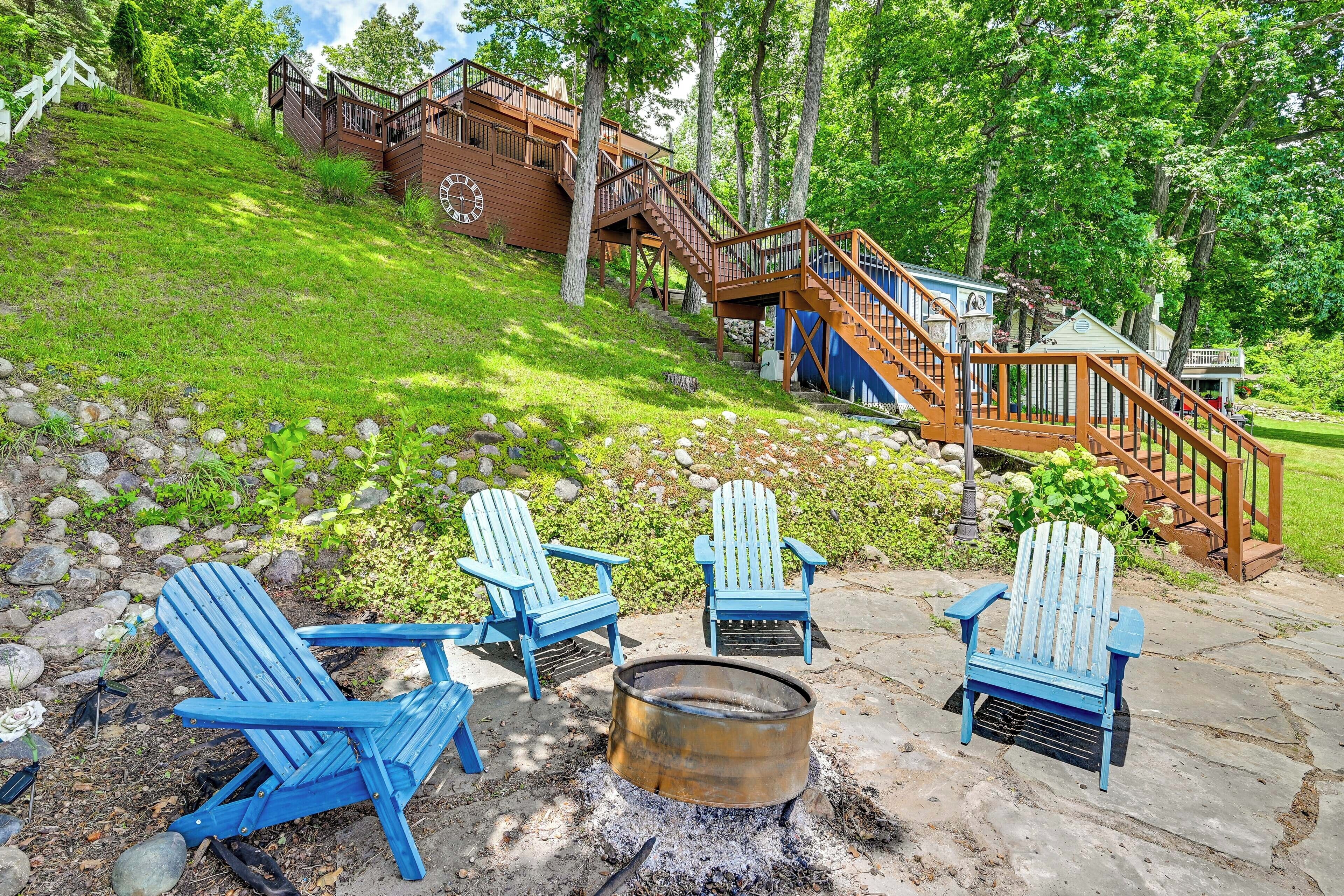 Une terrasse en bois avec des fauteuils Adirondack, un foyer et un escalier menant à un chalet.