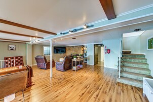 Amplia sala de estar con suelo de madera, chimenea, escalera y comedor con mesa y sillas de madera.