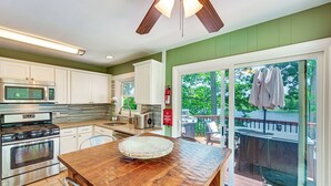 Una cocina con una mesa de madera, electrodomésticos de acero inoxidable y vistas al exterior.