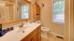 Ein Badezimmer mit Waschbecken, Spiegel, Schrank, Toilette und Fenster.