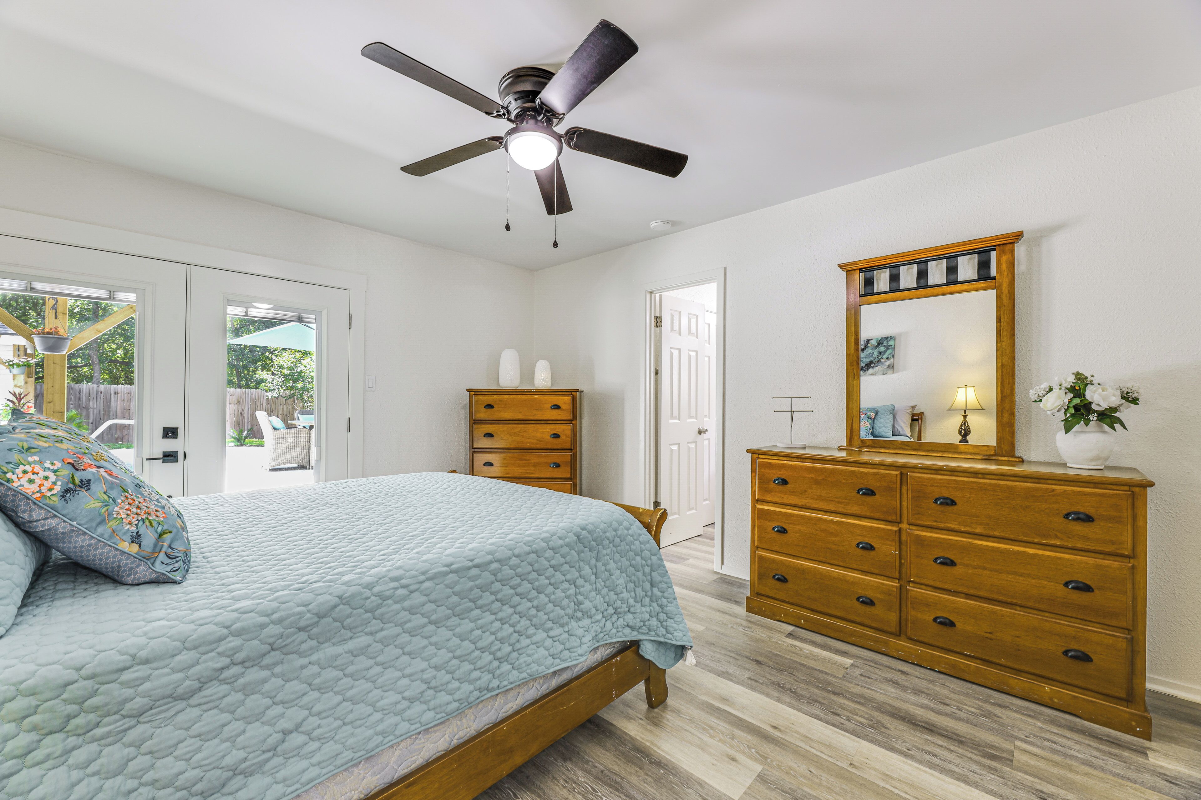 A bedroom with a bed, a ceiling fan, a dresser, and a mirror.