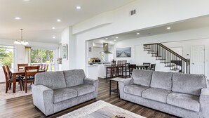 A spacious living area with two grey sofas, a coffee table, and a dining area with wooden furniture. - Modern Waterfront Home w/ Dock & Views in Deale (Deale)