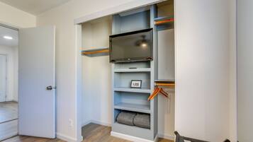 A walk-in closet with shelves, a flat-screen TV, and a door.